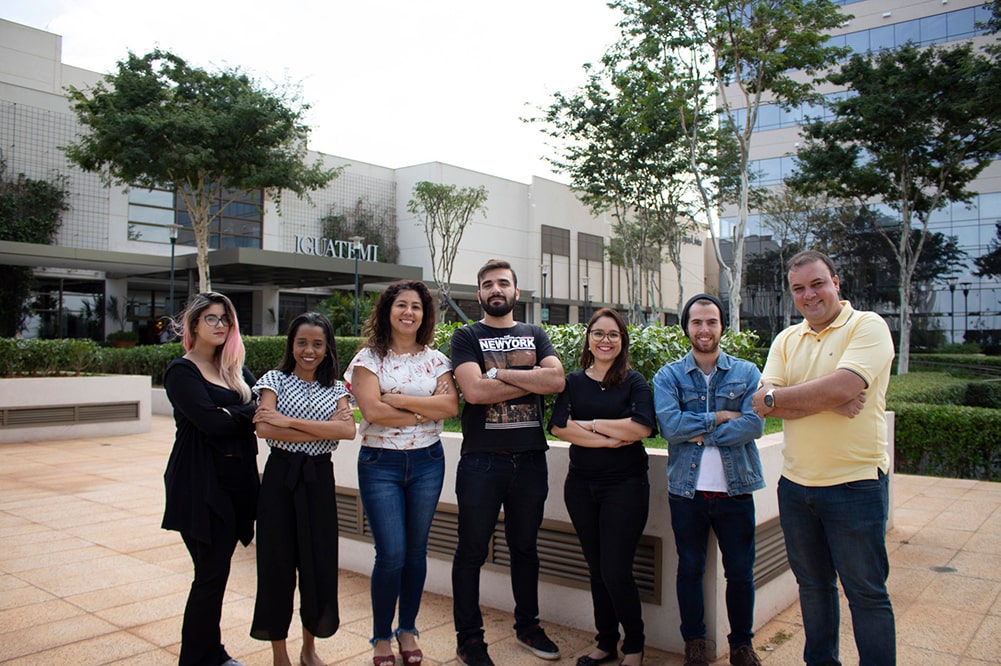 Uma foto da equipe da agência de marketing digital SmMind na frente do prédio que a agência é localizada.