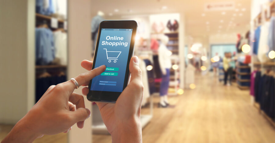 imagem de uma pessoa segurando o celular dentro de uma loja de roupas, representando a ideia de nome para loja virtual de roupas